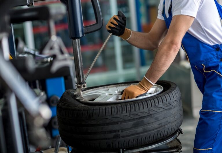 A tire-mounting technician is fitting a new tire onto a wheel rim in Central Minnesota