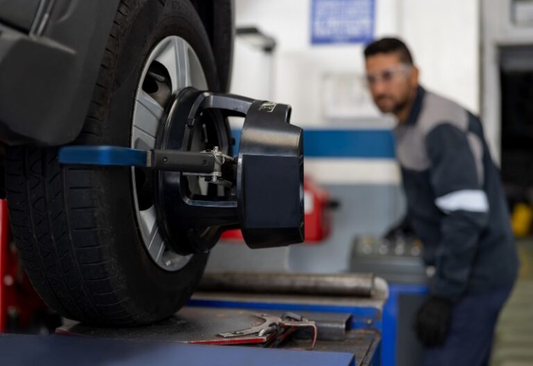 Automotive technician checking tire alignment in Central Minnesota